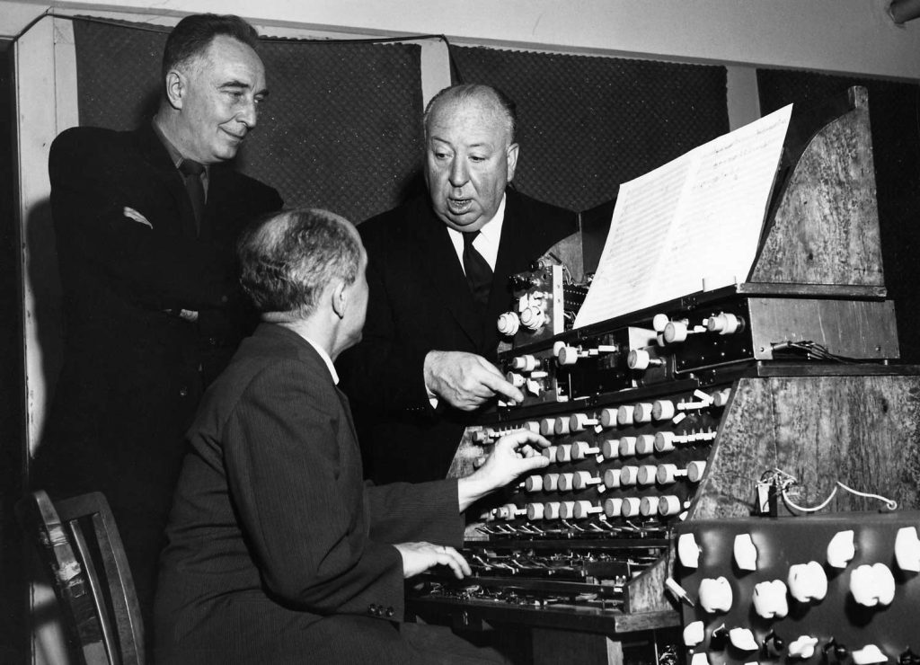 Hitchcock works on the sounds of “The Birds” with sound effects producer-composers Remi Gassmann and Oskar Sala at a MixturTrautonium synthesizer